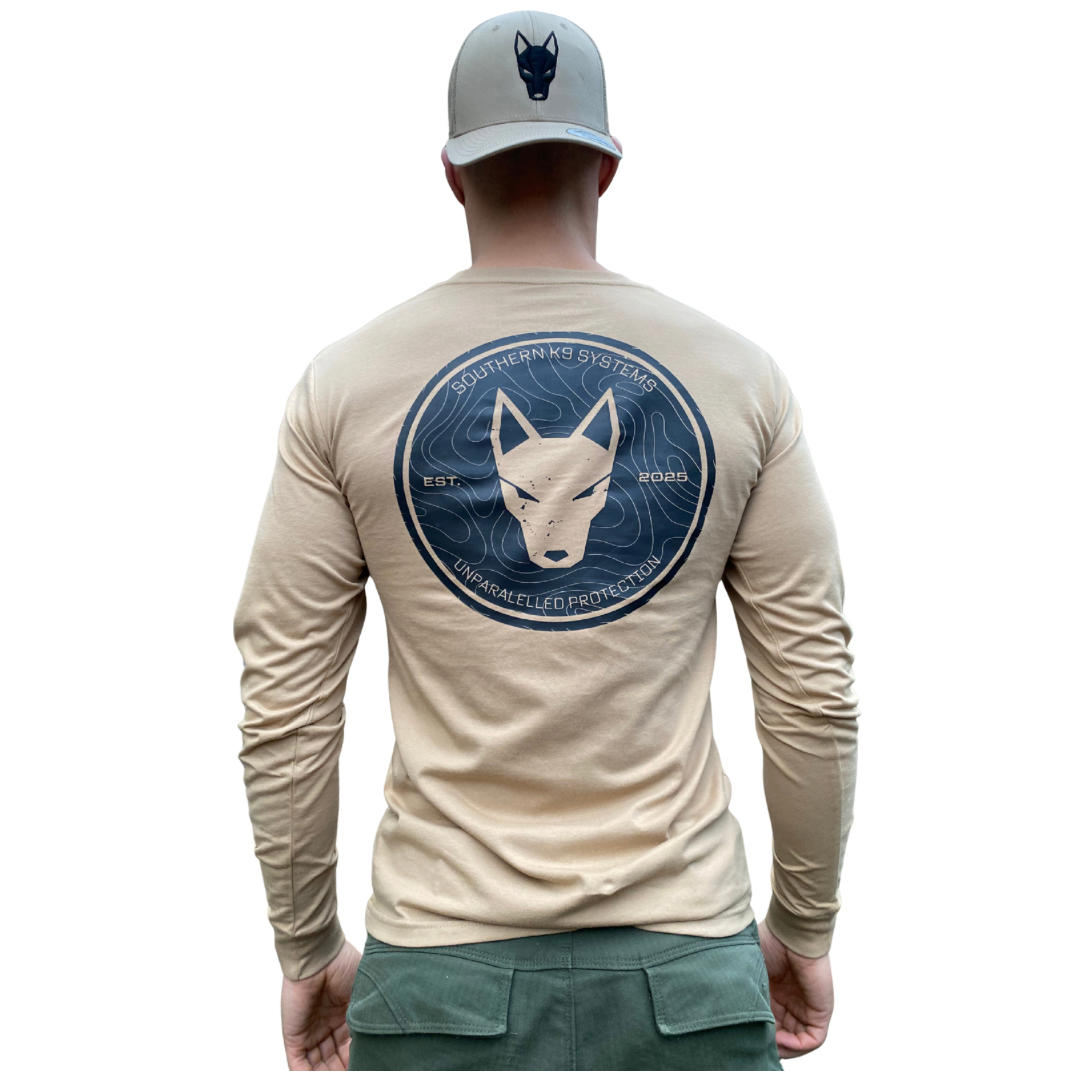 Man wearing a beige long-sleeve shirt with a K9 logo and a cap on a white background